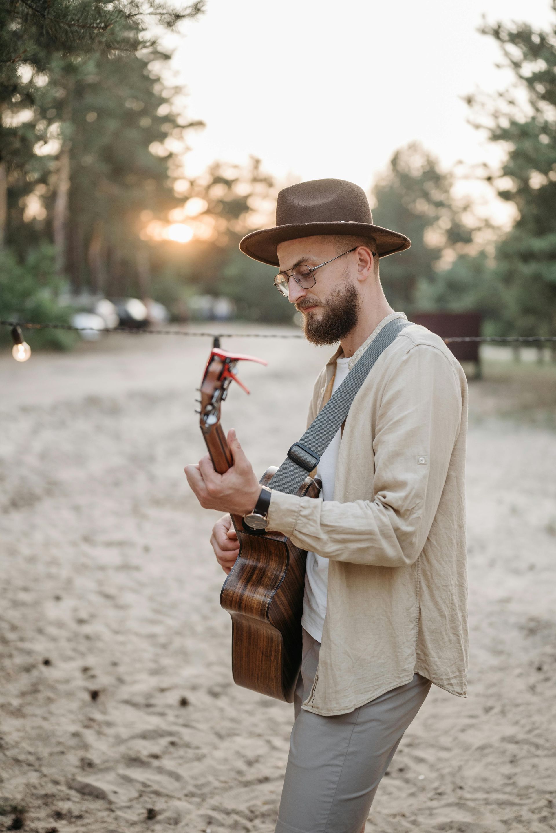 A man in a hat is playing a guitar on the beach.
