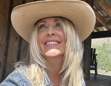 A woman wearing a cowboy hat is smiling for the camera