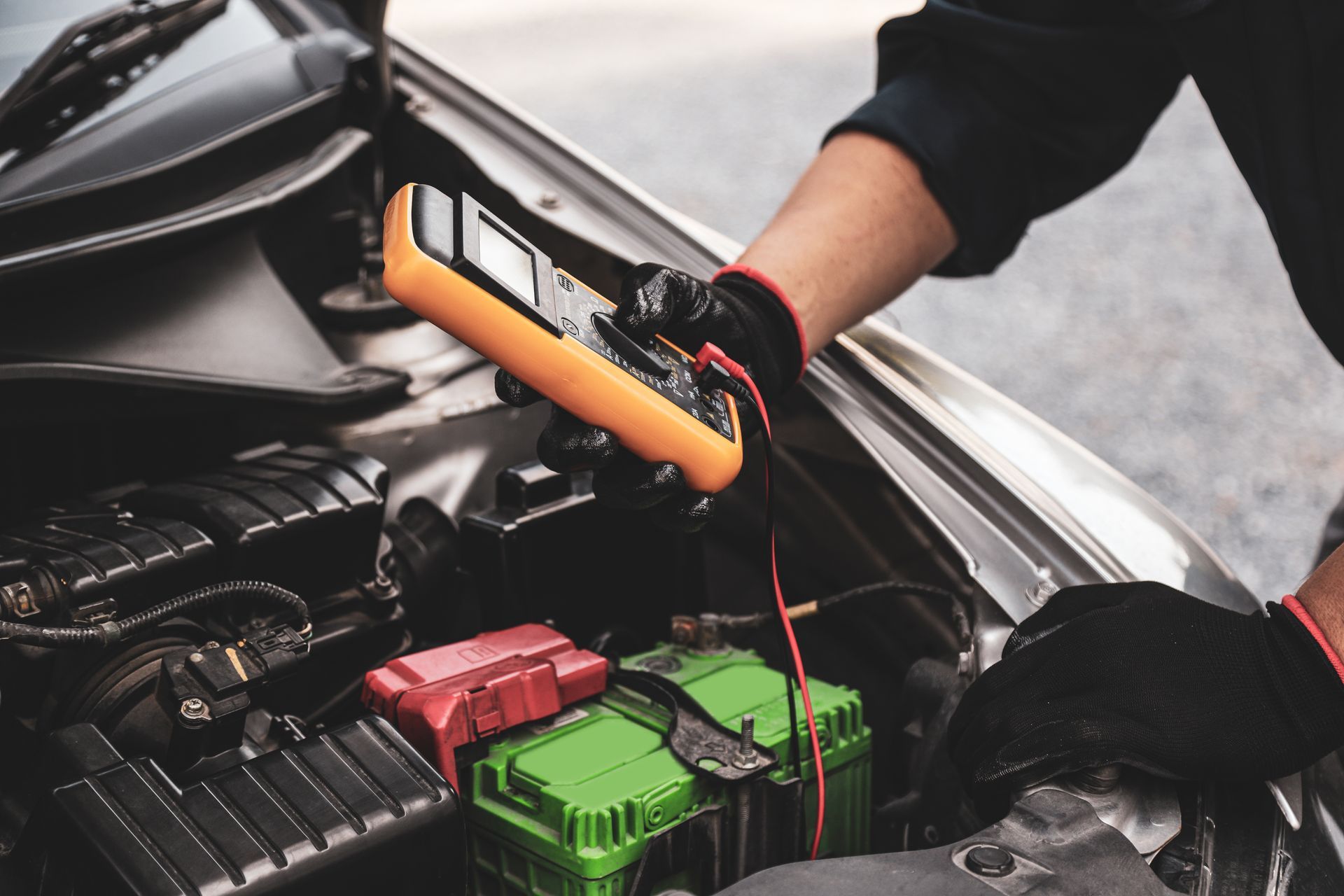 A partial view of a car mechanic using a voltmeter to check the voltage of a car battery. A partial view of a car mechanic using a voltmeter to check the voltage of a car battery.