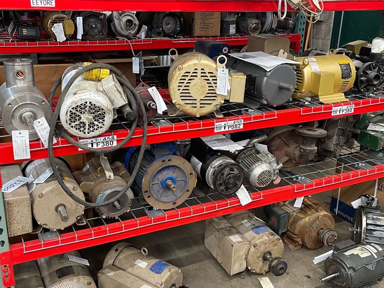 A warehouse shelf filled with various industrial electric motors of different sizes, colors, and shapes. A warehouse shelf filled with various industrial electric motors of different sizes, colors, and shapes.