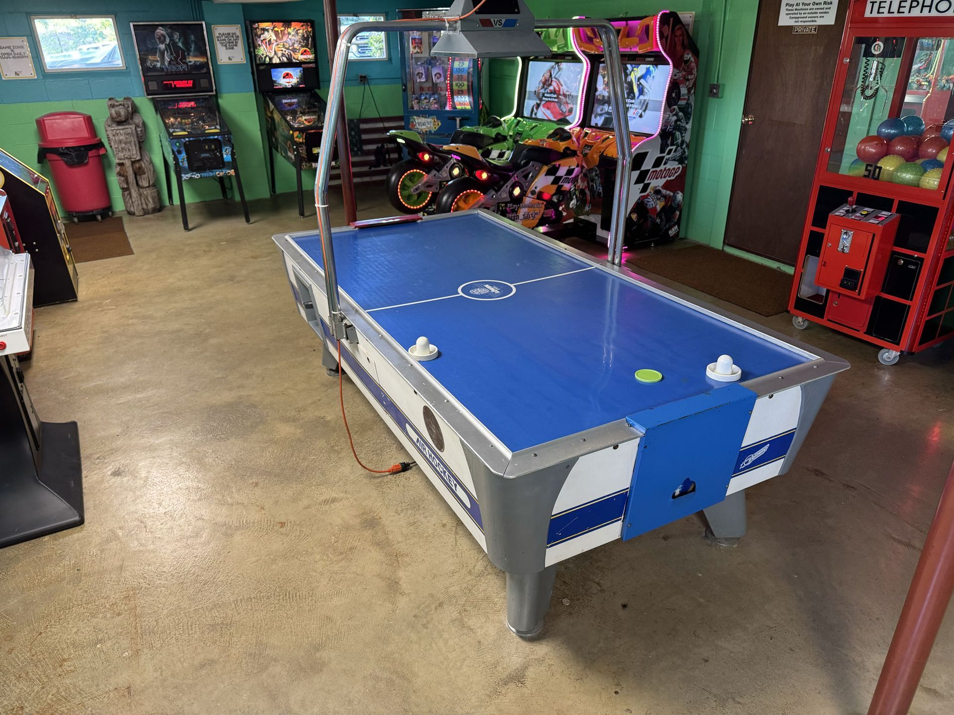 Air hockey table in a brightly lit arcade with other games.