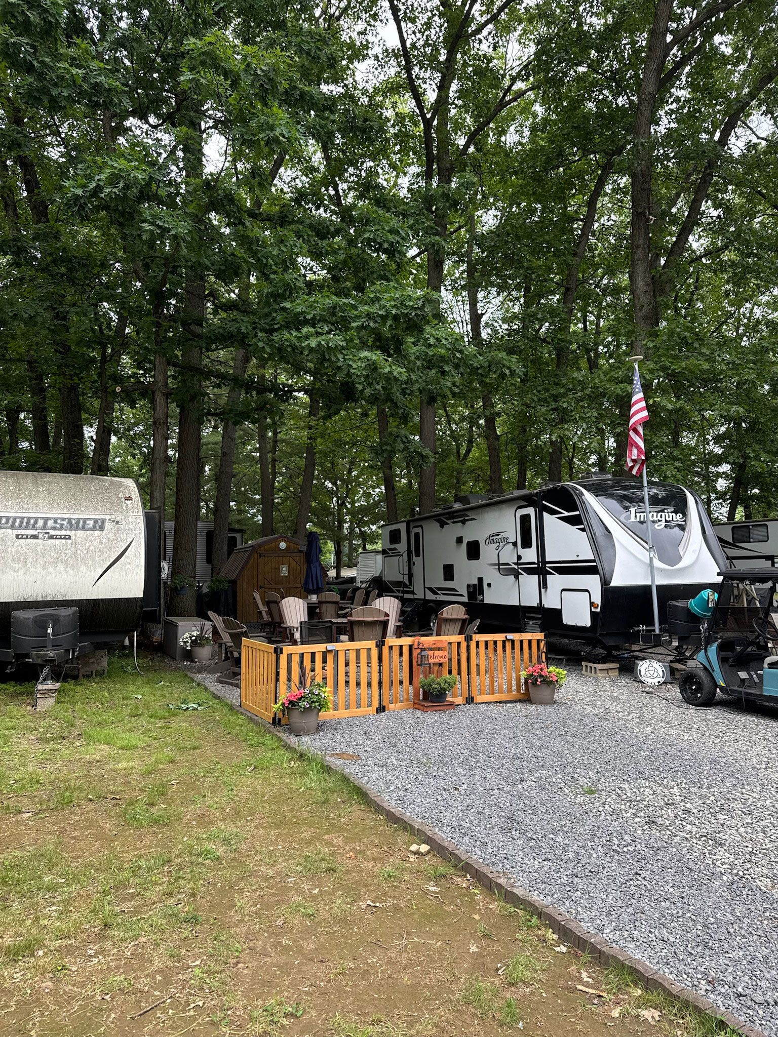 Campground with RVs parked among trees, gravel driveways, and wooden fences.