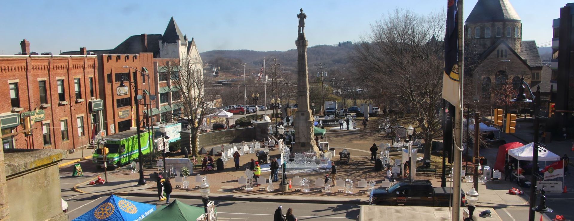 View of a downtown area with a monument, buildings, and people. Sunny day.