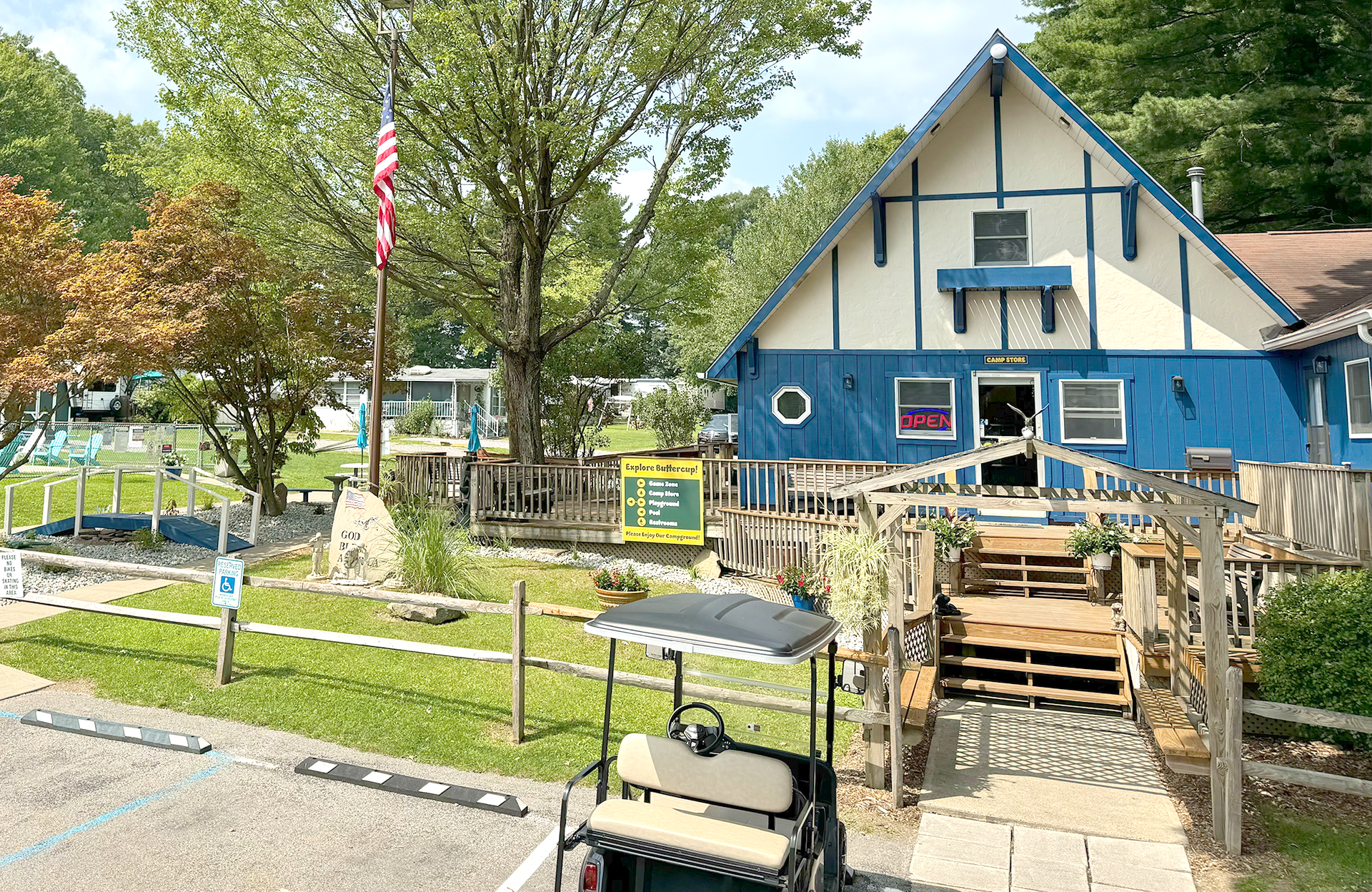Blue and white building with a wooden deck, a golf cart, and an American flag.