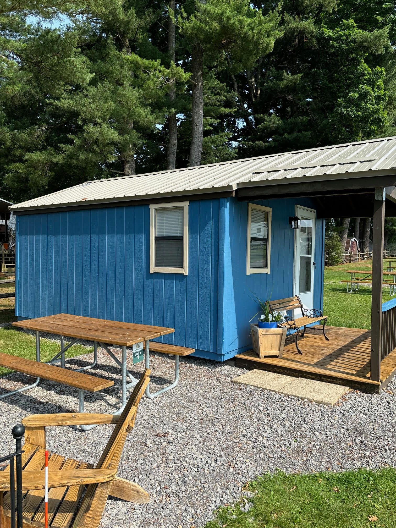 Blue cabin with picnic table and small porch.