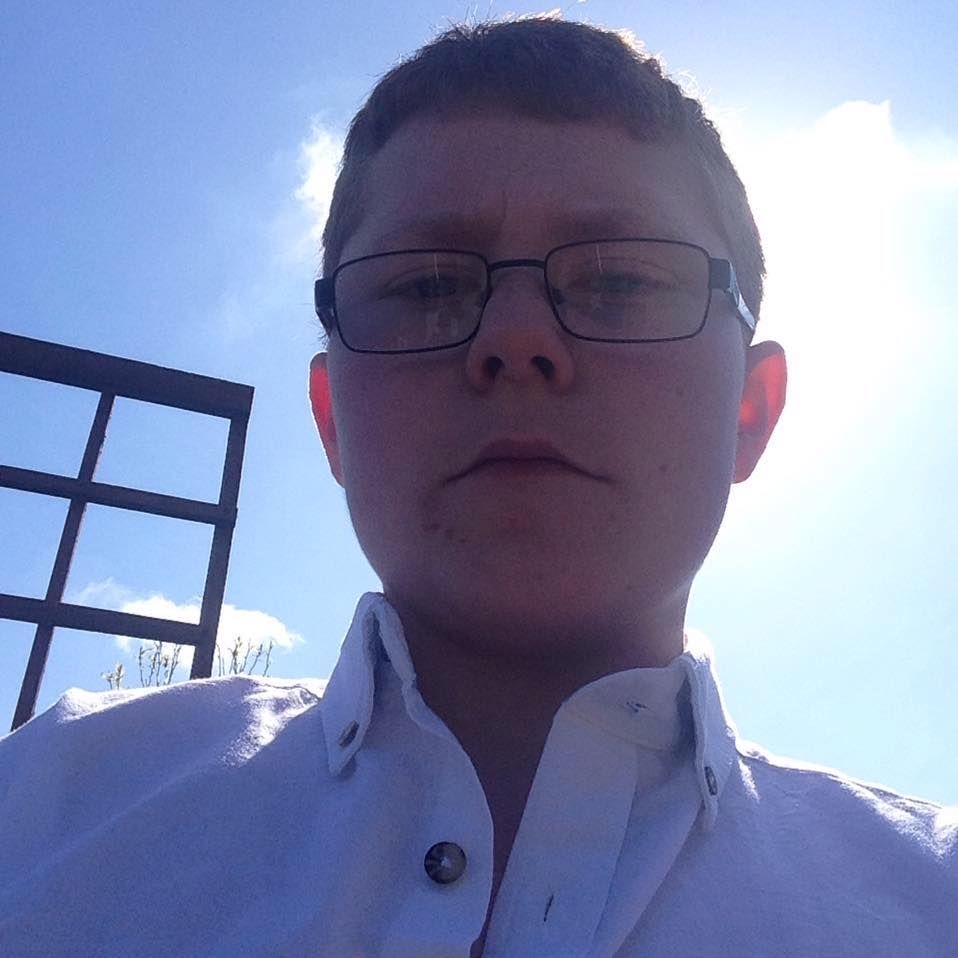 A man wearing glasses and a white shirt takes a selfie