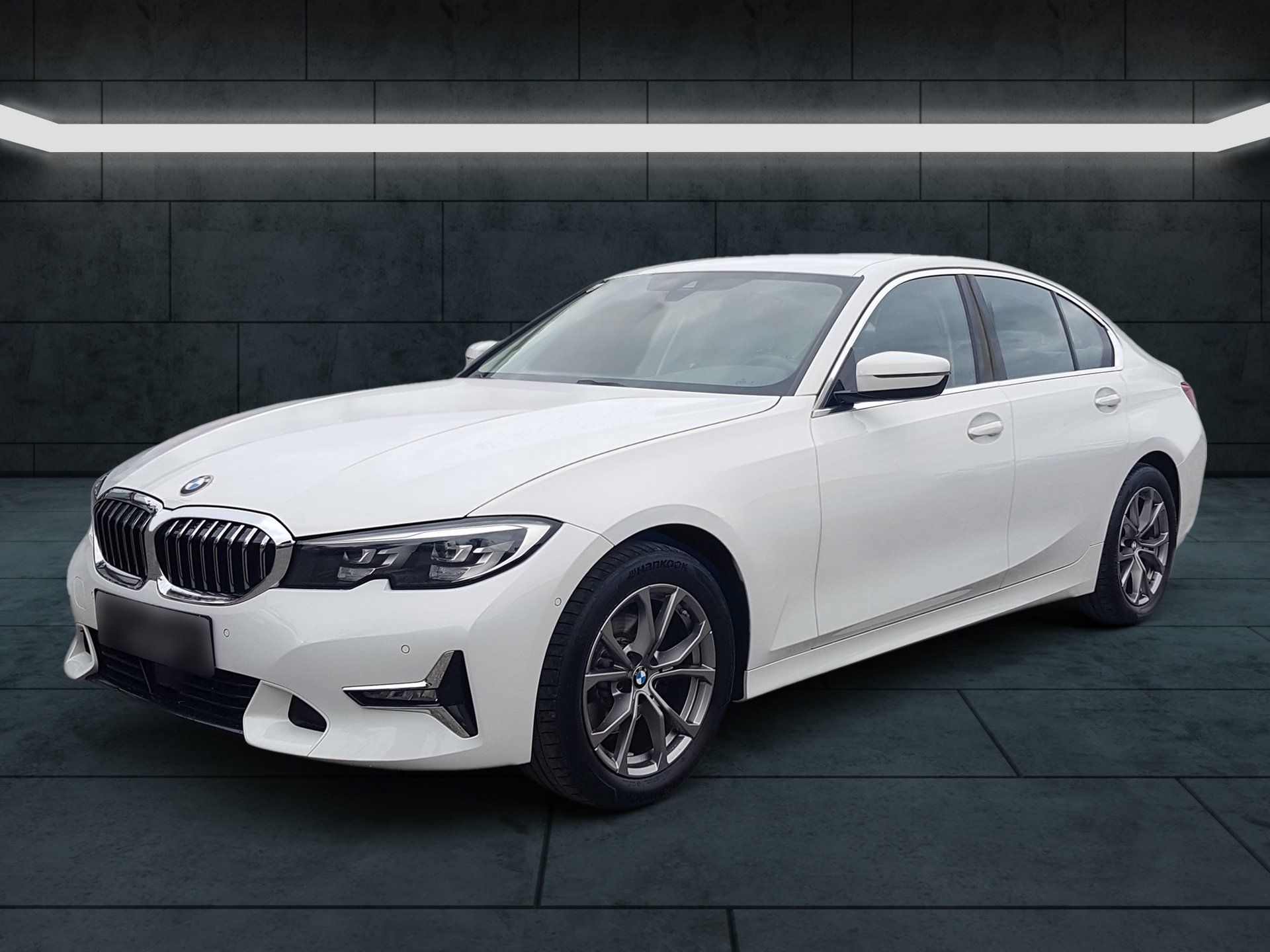 Eine weiße BMW-Limousine parkt in einem Ausstellungsraum.