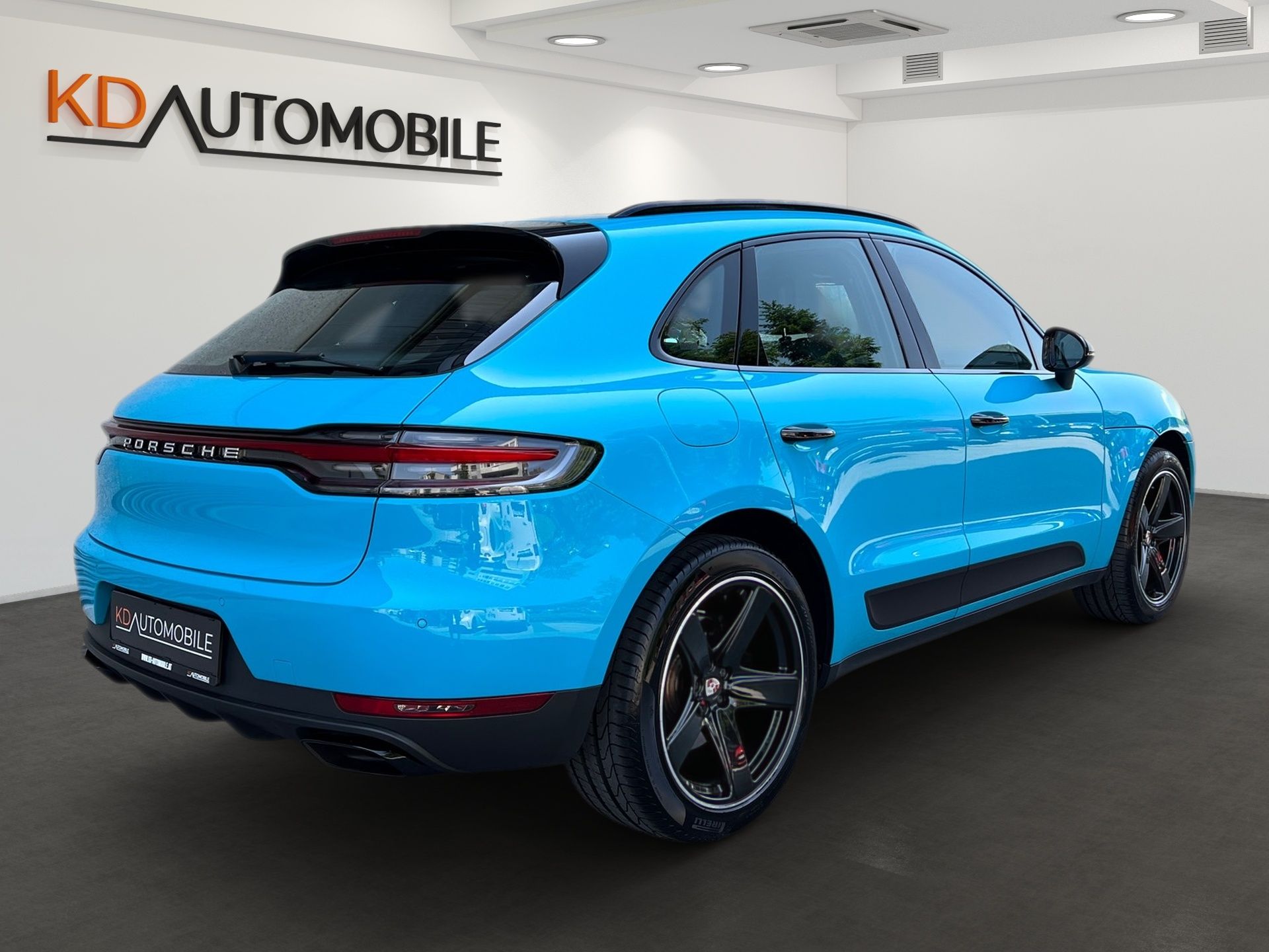 Ein blauer Porsche Macan Turbo steht in einem digitalen Showroom von CARMERA, Referenzbeispiel KD Automobile