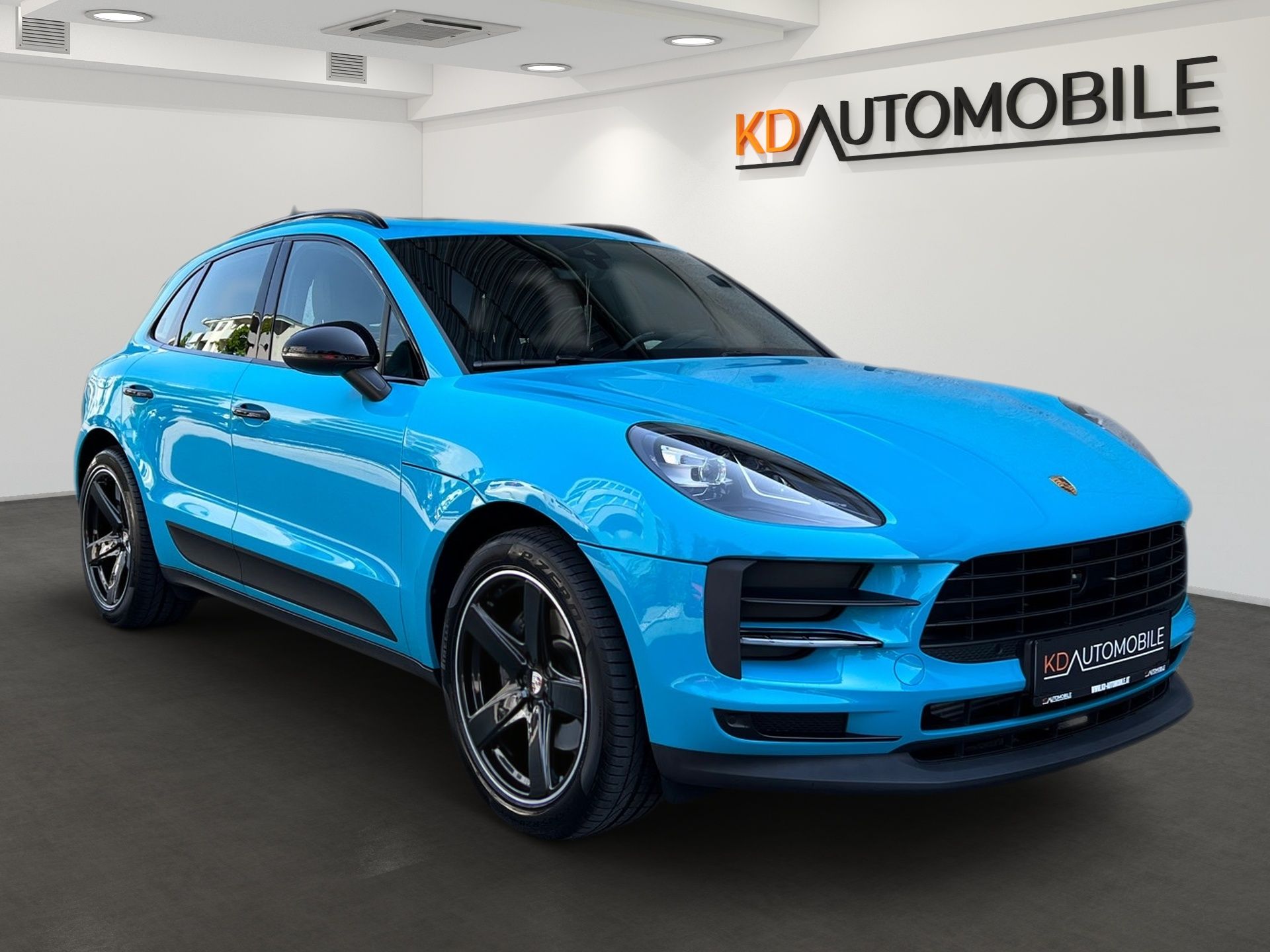 Ein blauer Porsche Macan Turbo steht in einem digitalen Showroom von CARMERA, Referenzbeispiel KD Automobile