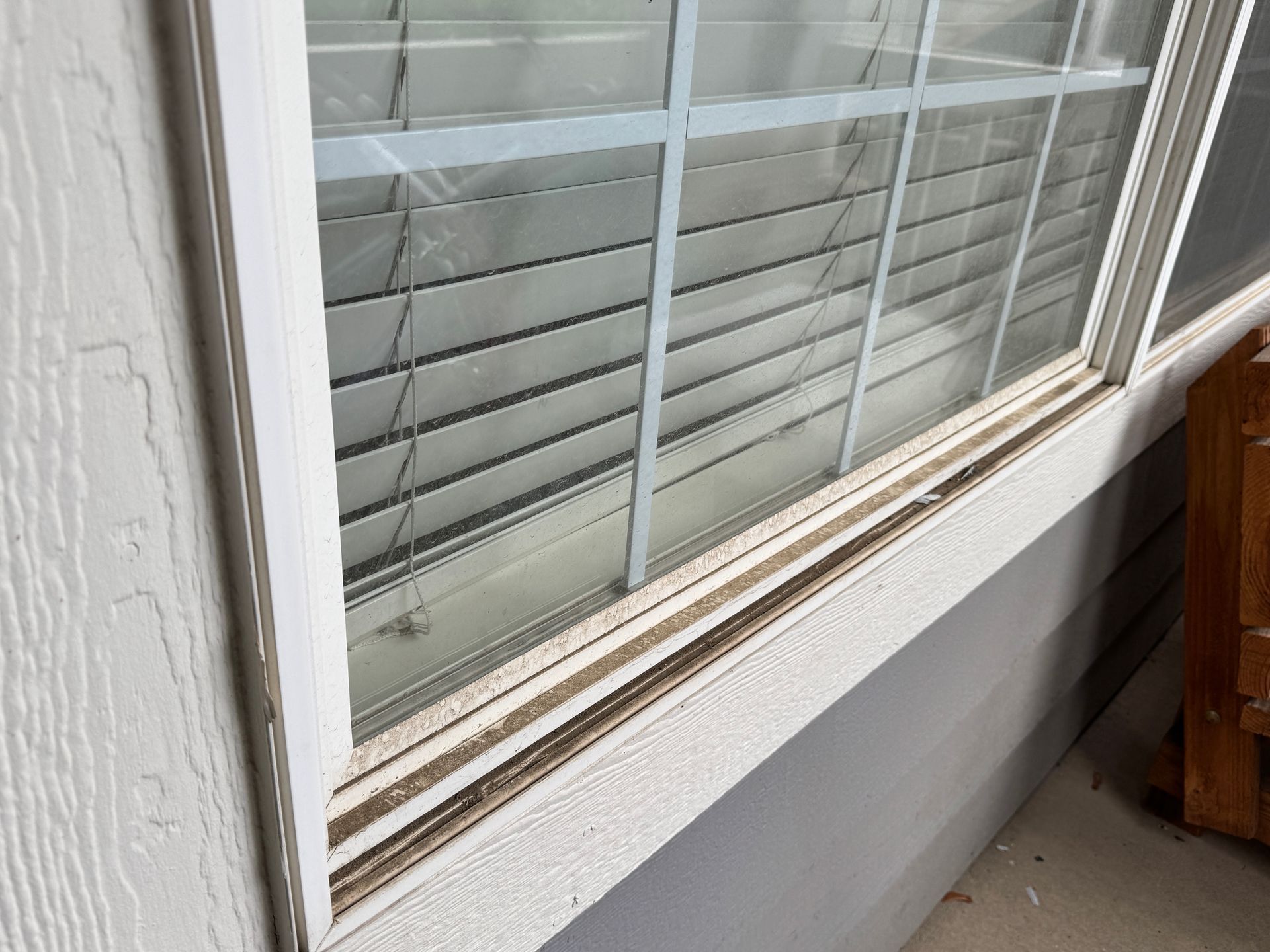 A close up of a dirty window inHighlands Ranch with blinds on it.