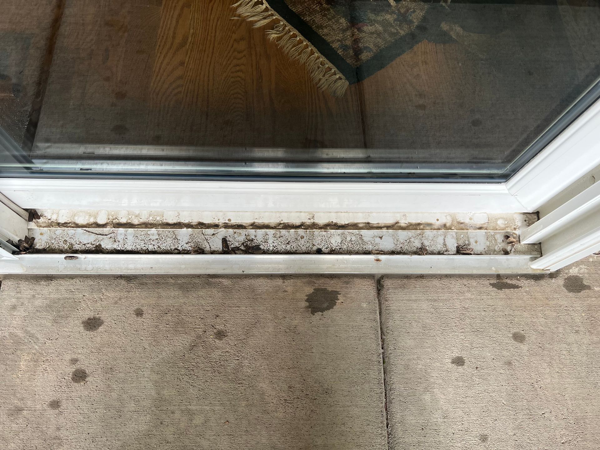 A dirty sliding glass door is sitting on a tiled floor.