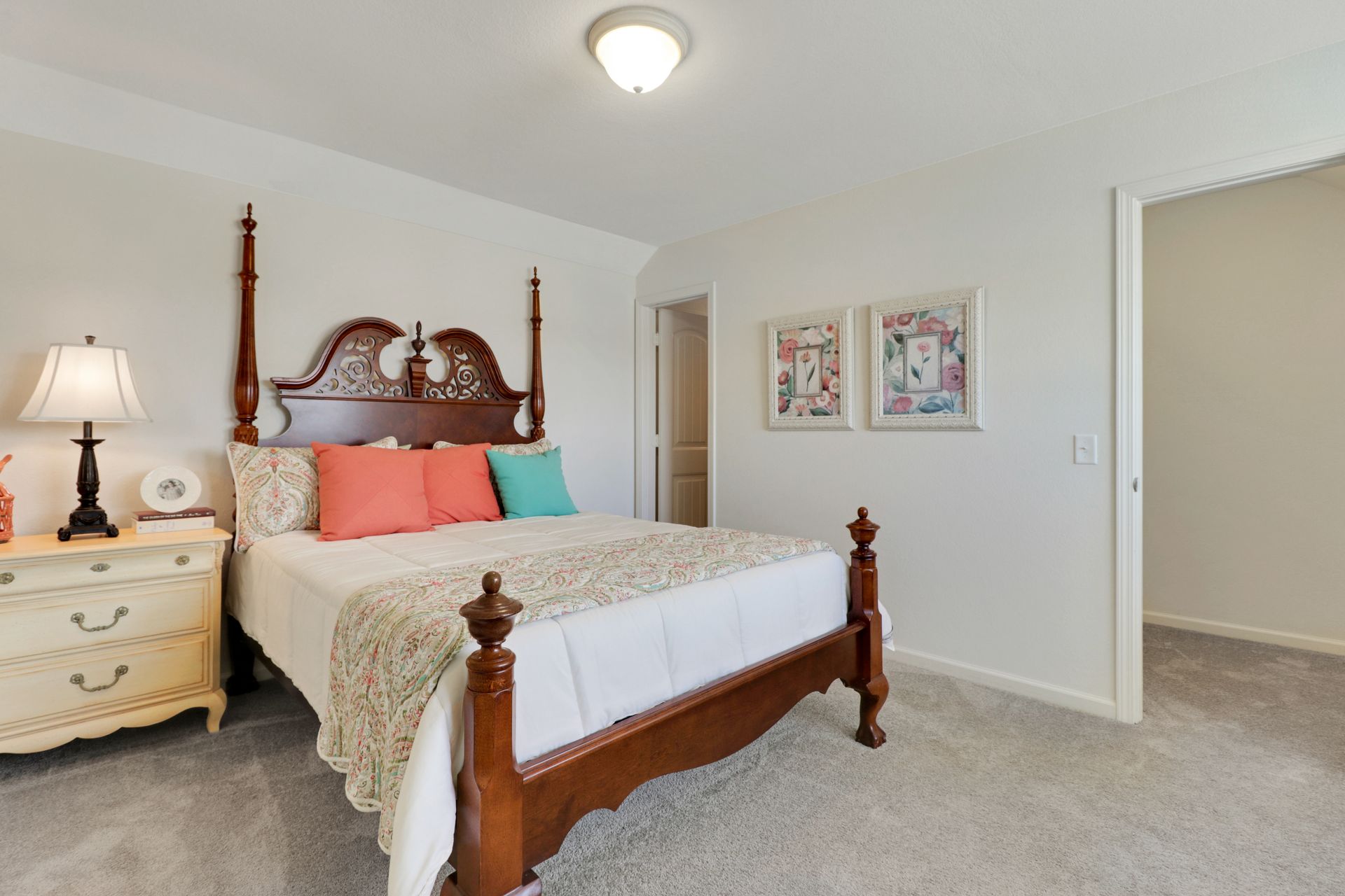 A bedroom with a bed , nightstand , lamp and dresser.