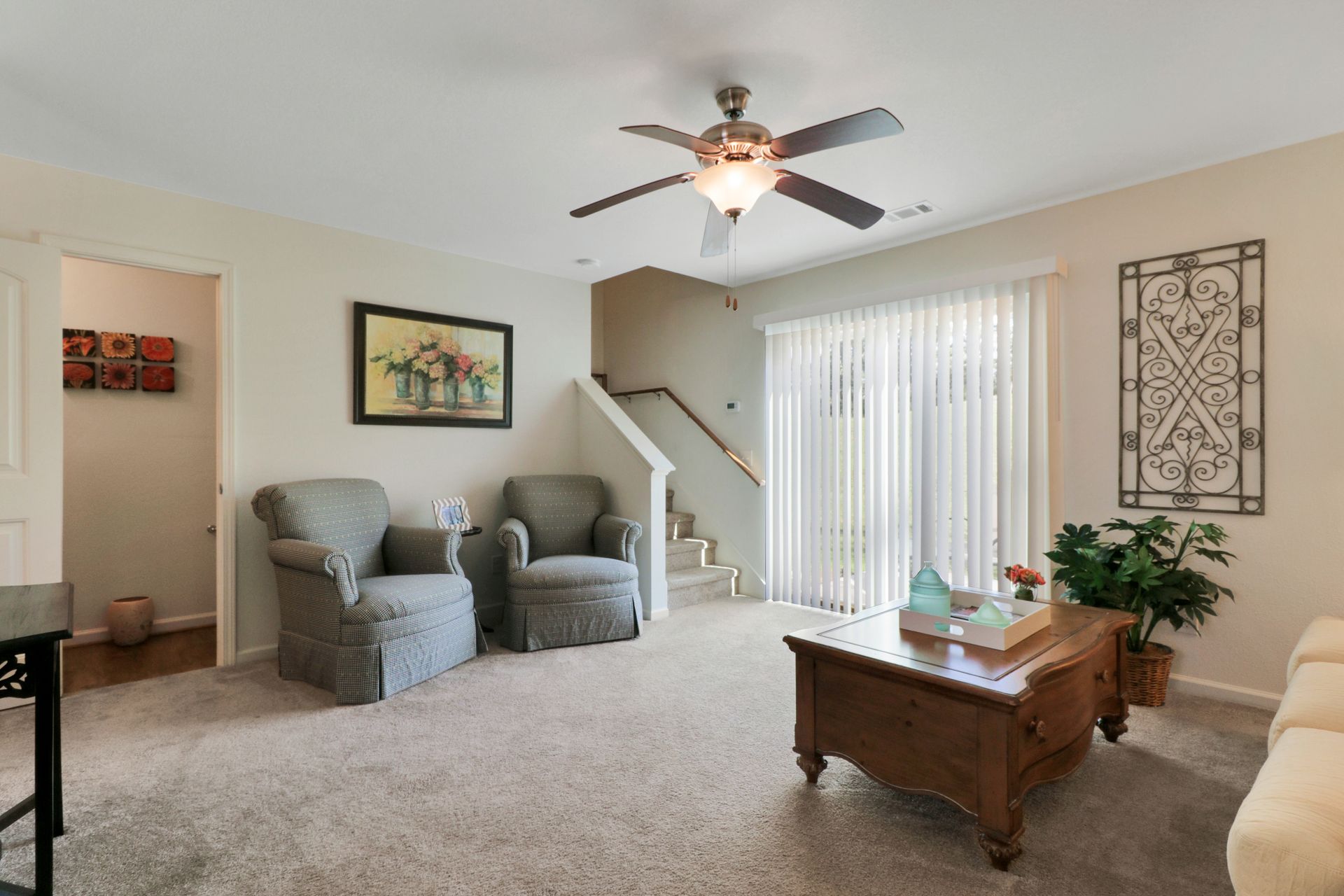 A living room with two chairs and a coffee table and a ceiling fan