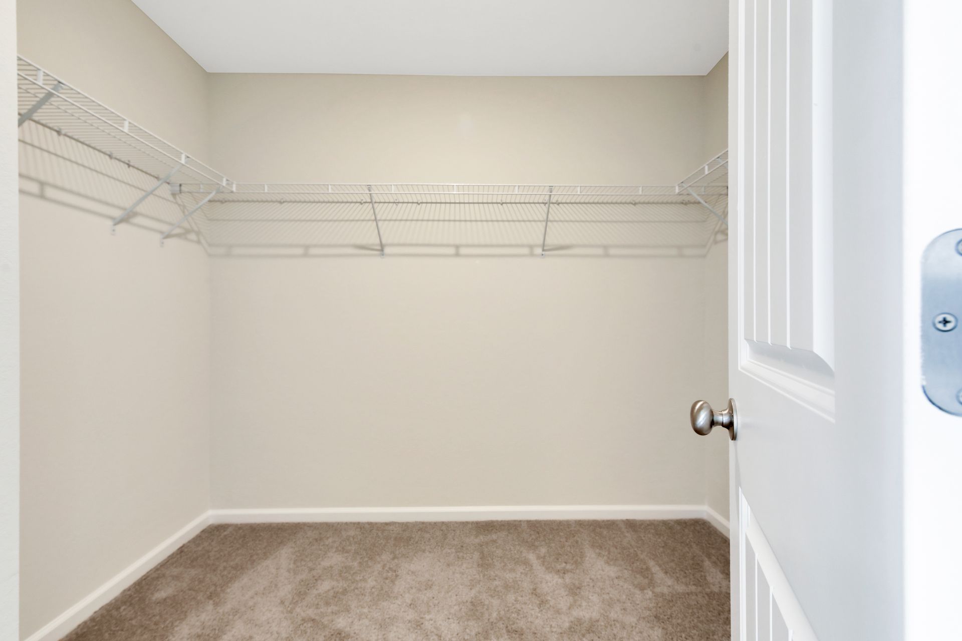 An empty walk in closet with shelves and a door.