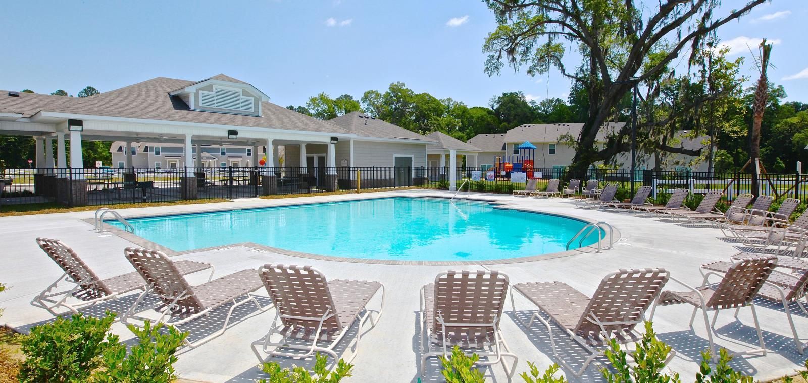 A large swimming pool surrounded by chairs and a house