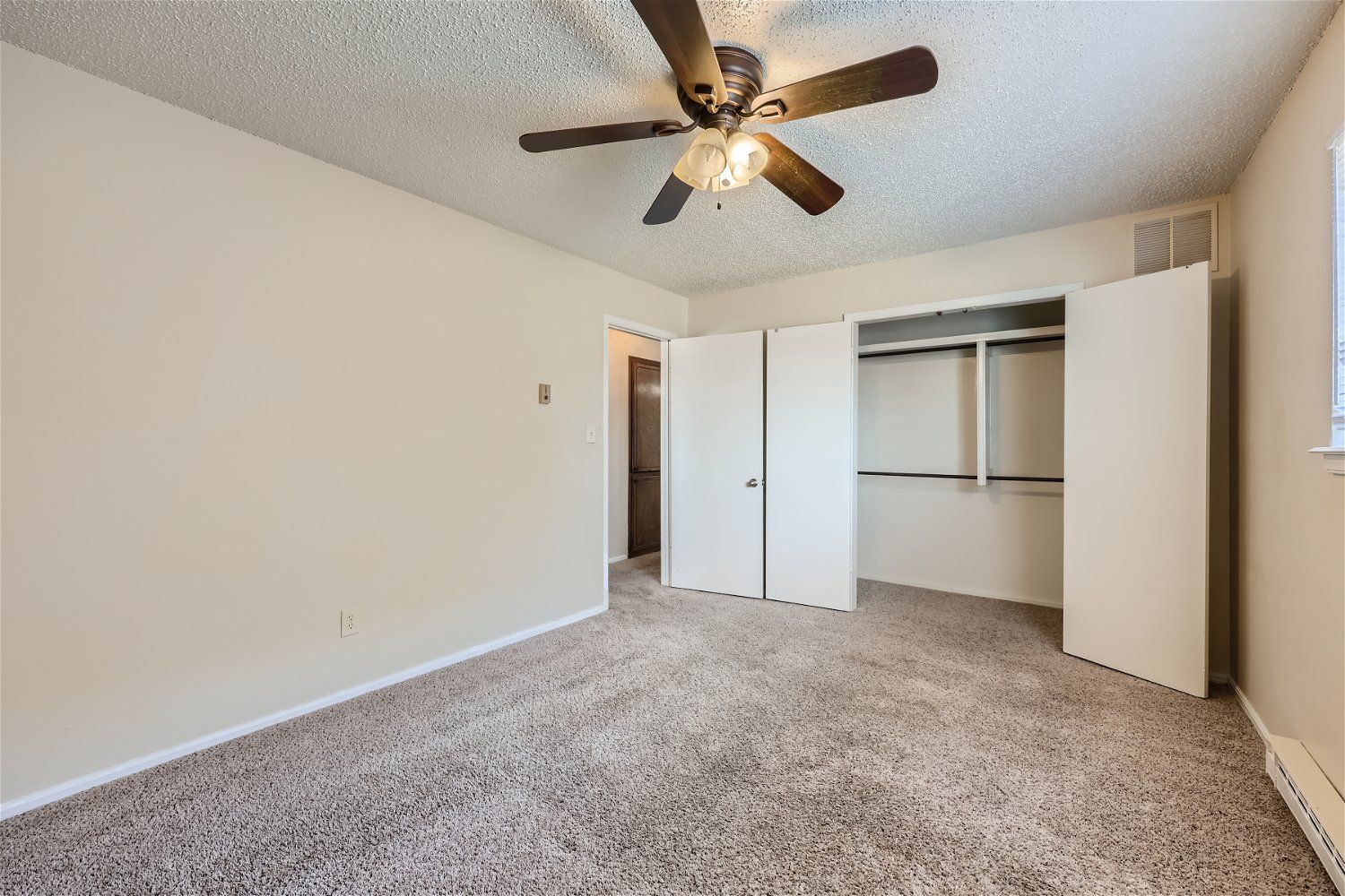 This Copperstone Point bedroom has beige walls, carpet, a window with blinds, and a ceiling fan.