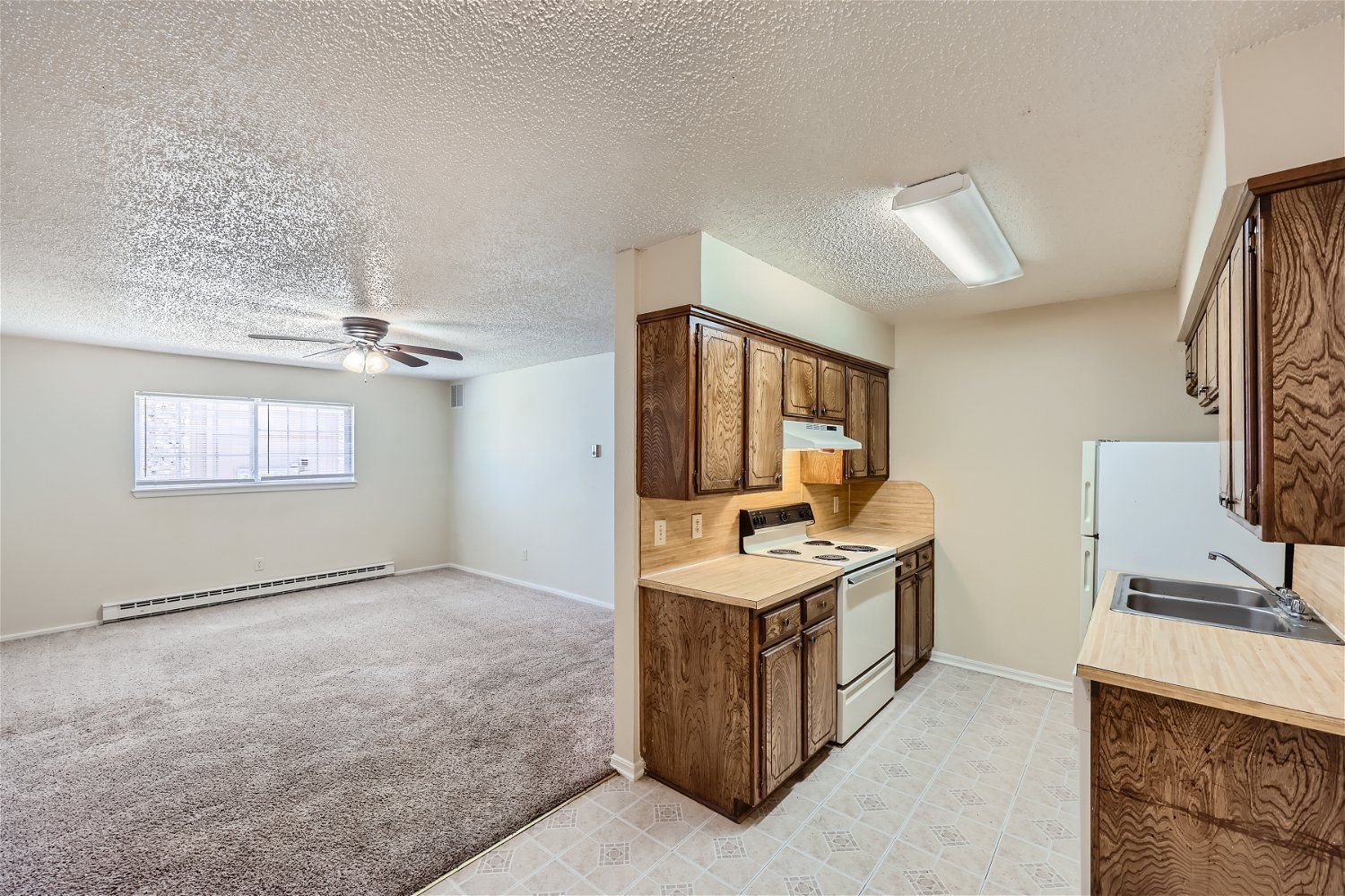 Interior view of an Copperstone apartment kitchen with wooden cabinets, stove, and sink.