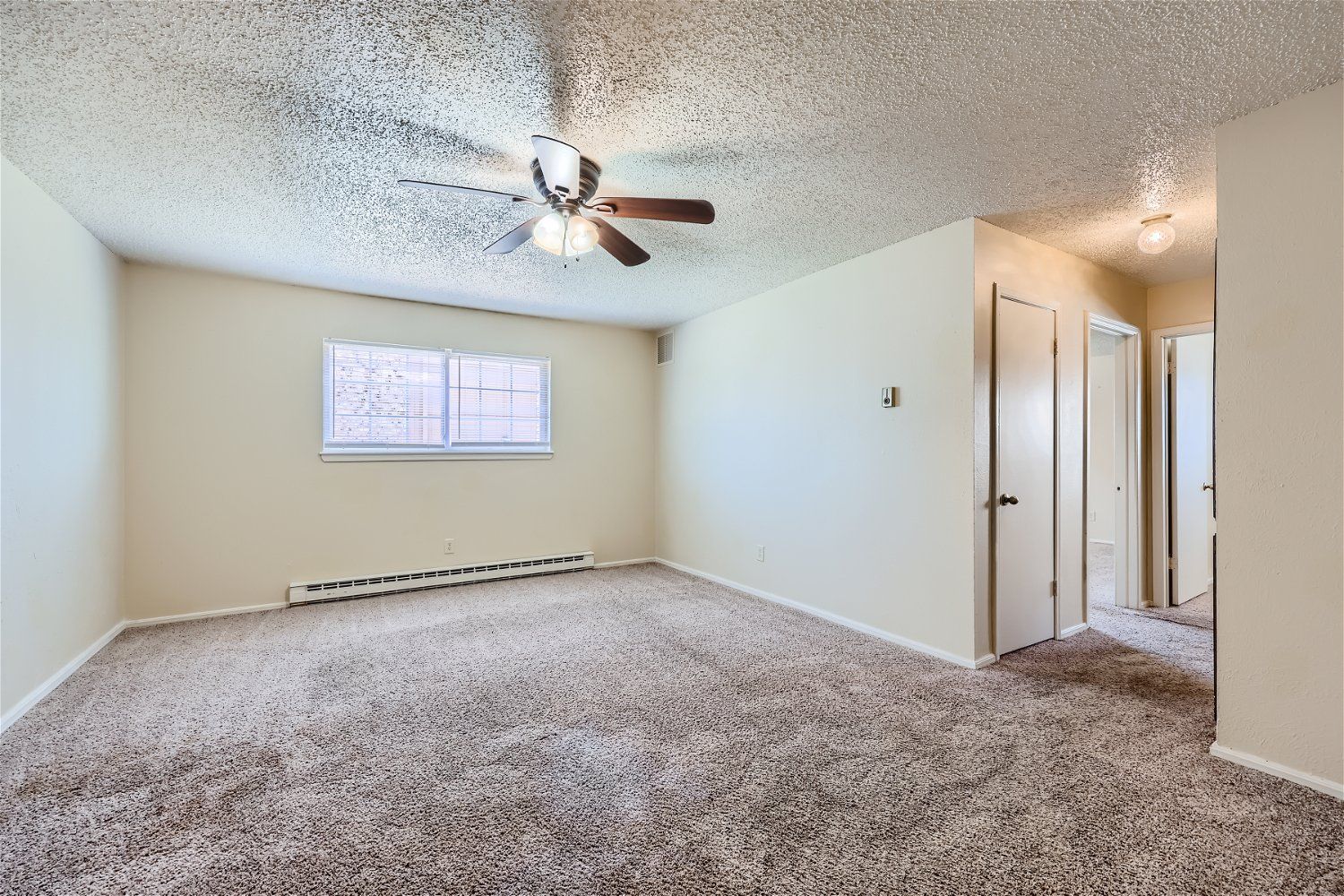This Copperstone Point living room has beige walls, plush carpet, ceiling fan, and a window.