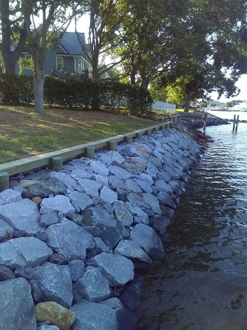A Sculpture Is Sitting on Top of A Pile of Rocks Next to A Body of Water.