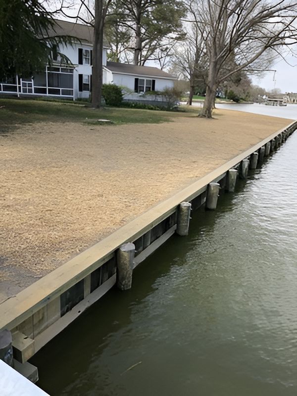 A House Is Sitting on The Shore of A Body of Water Next to A Dock.