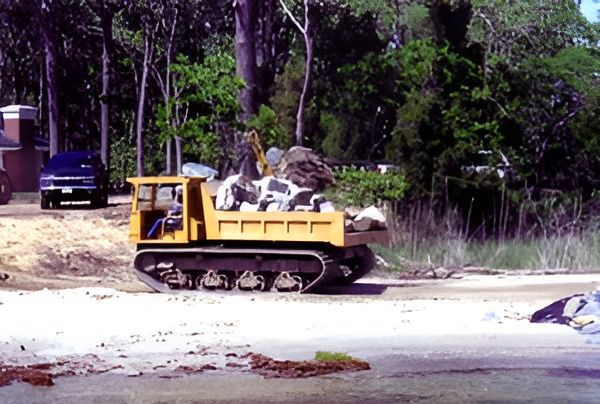 A Yellow Truck Is Driving Down a Road with Trees in The Background A Yellow Truck Is Driving Down a Road with Trees in The Background