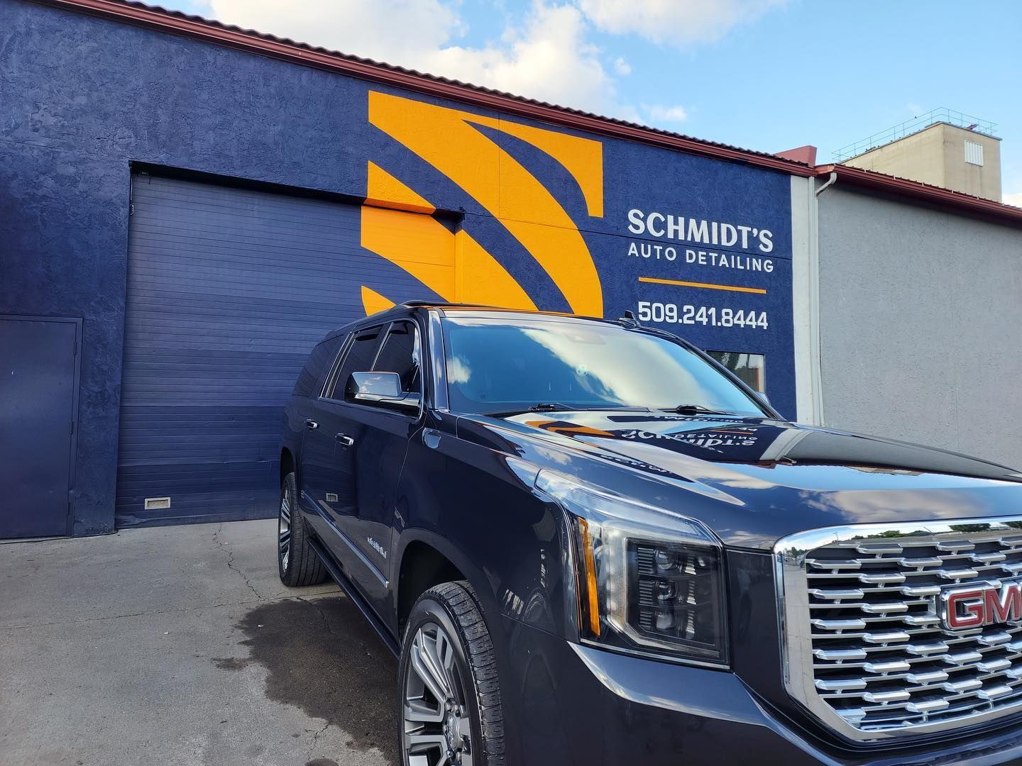 A black suv is parked in front of a building that says schmidt 's auto detailing