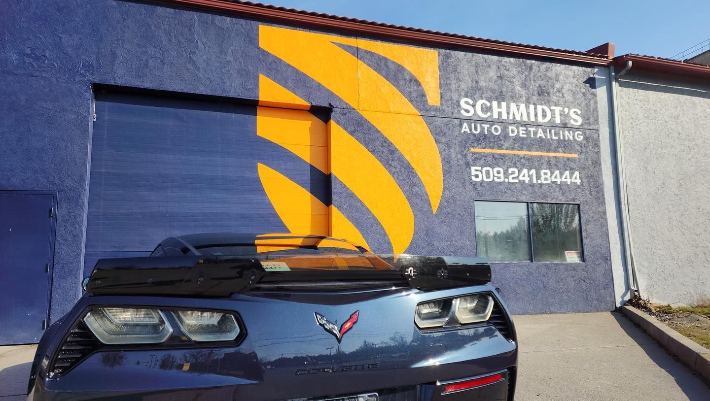A car is parked in front of a building that says schmidt 's auto detailing