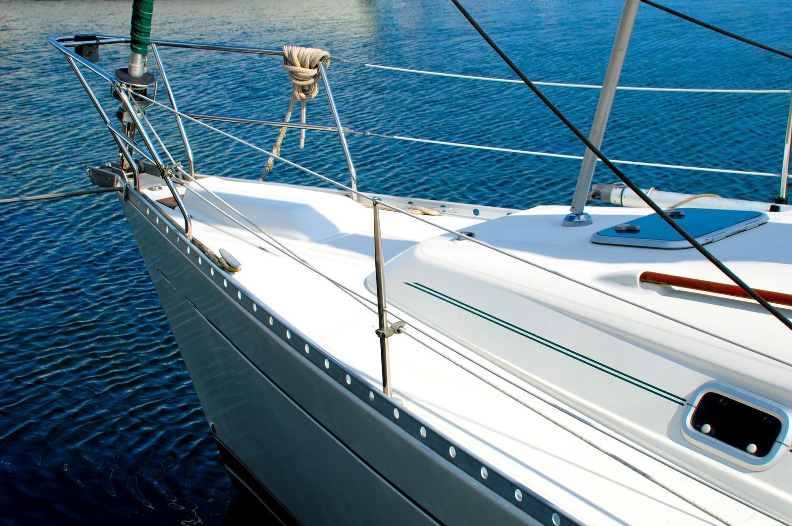 White sailboat bow on blue water. Green mast visible.