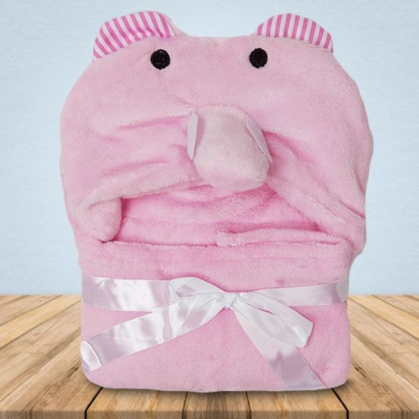 Een roze babydeken met capuchon en oortjes ligt op een houten tafel.