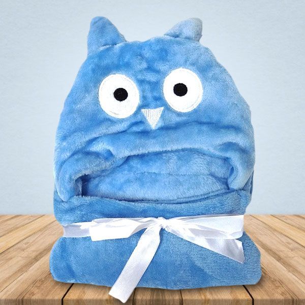 Een blauwe deken met een uil erop ligt op een houten tafel