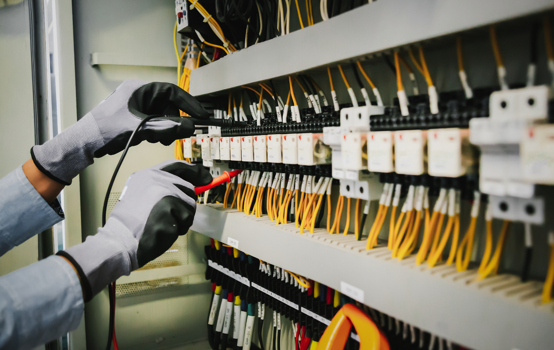 A person is working on an electrical panel with a voltmeter.