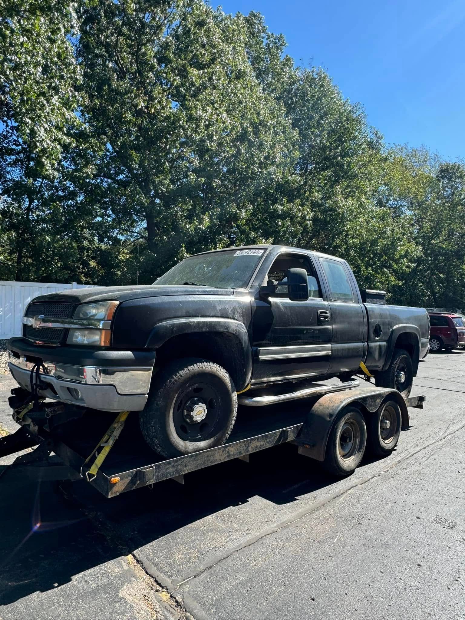 A black truck is sitting on top of a trailer.