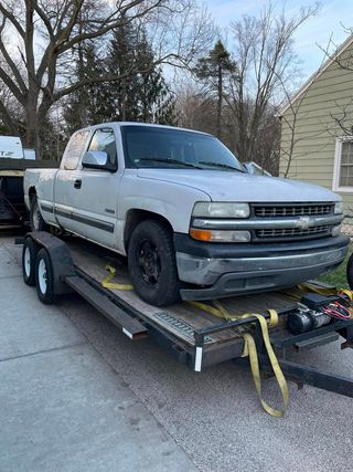 A white truck is sitting on top of a trailer.