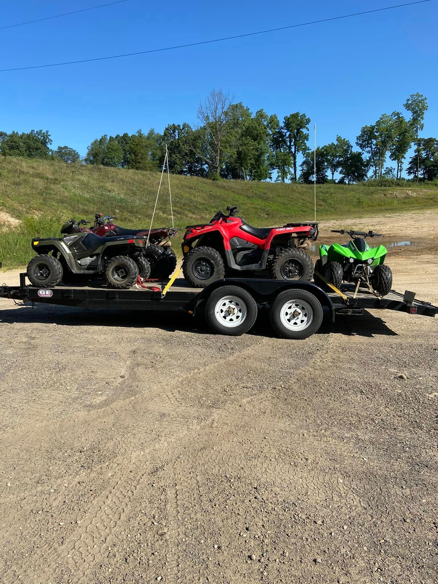 Two atvs are being towed on a trailer.