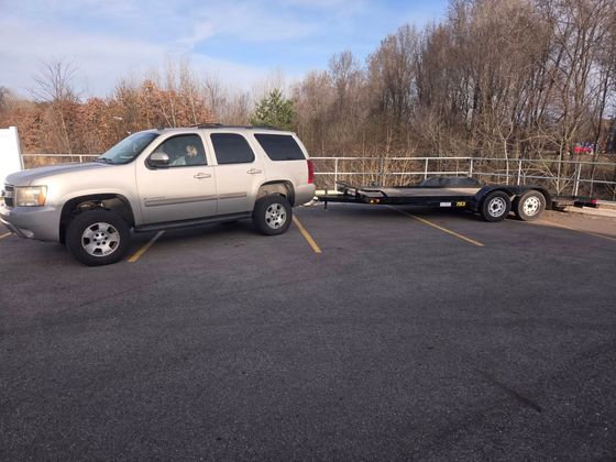 A silver suv is parked next to a trailer in a parking lot.