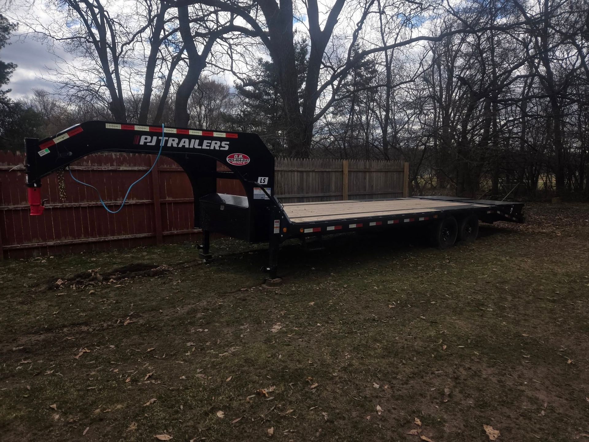 A flatbed trailer with a crane attached to it is parked in a yard.