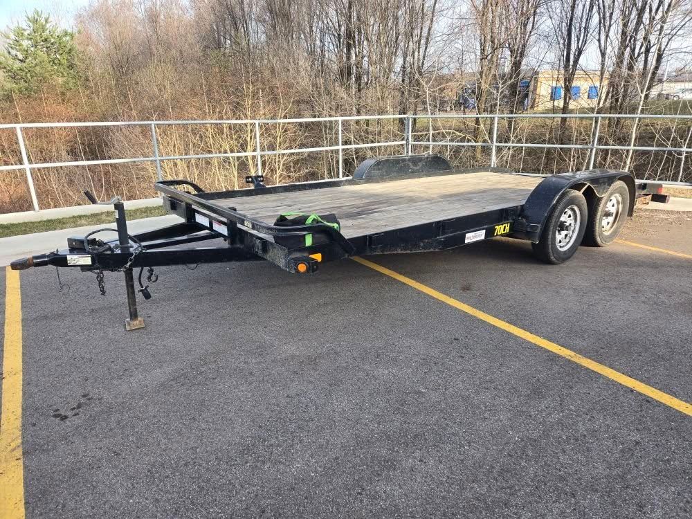 A flatbed trailer is parked in a parking lot.
