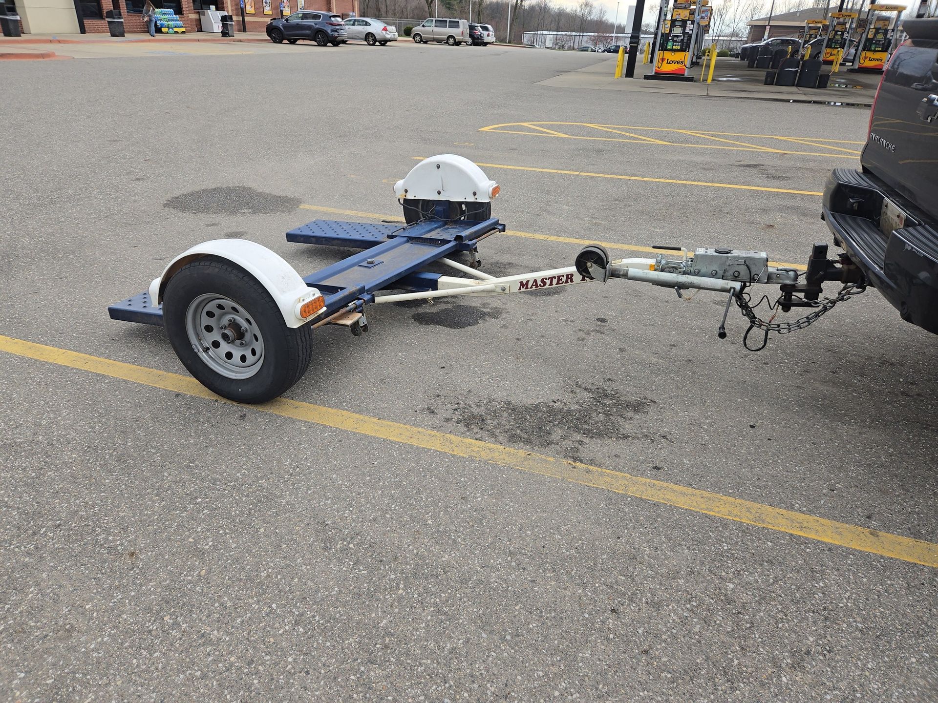 A trailer is being towed by a truck in a parking lot.
