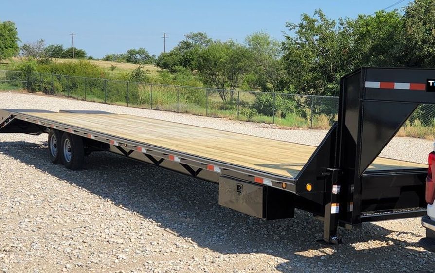 A flatbed trailer is parked on a gravel road.