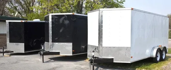 A dumpster filled with leaves is parked in a grassy yard.
