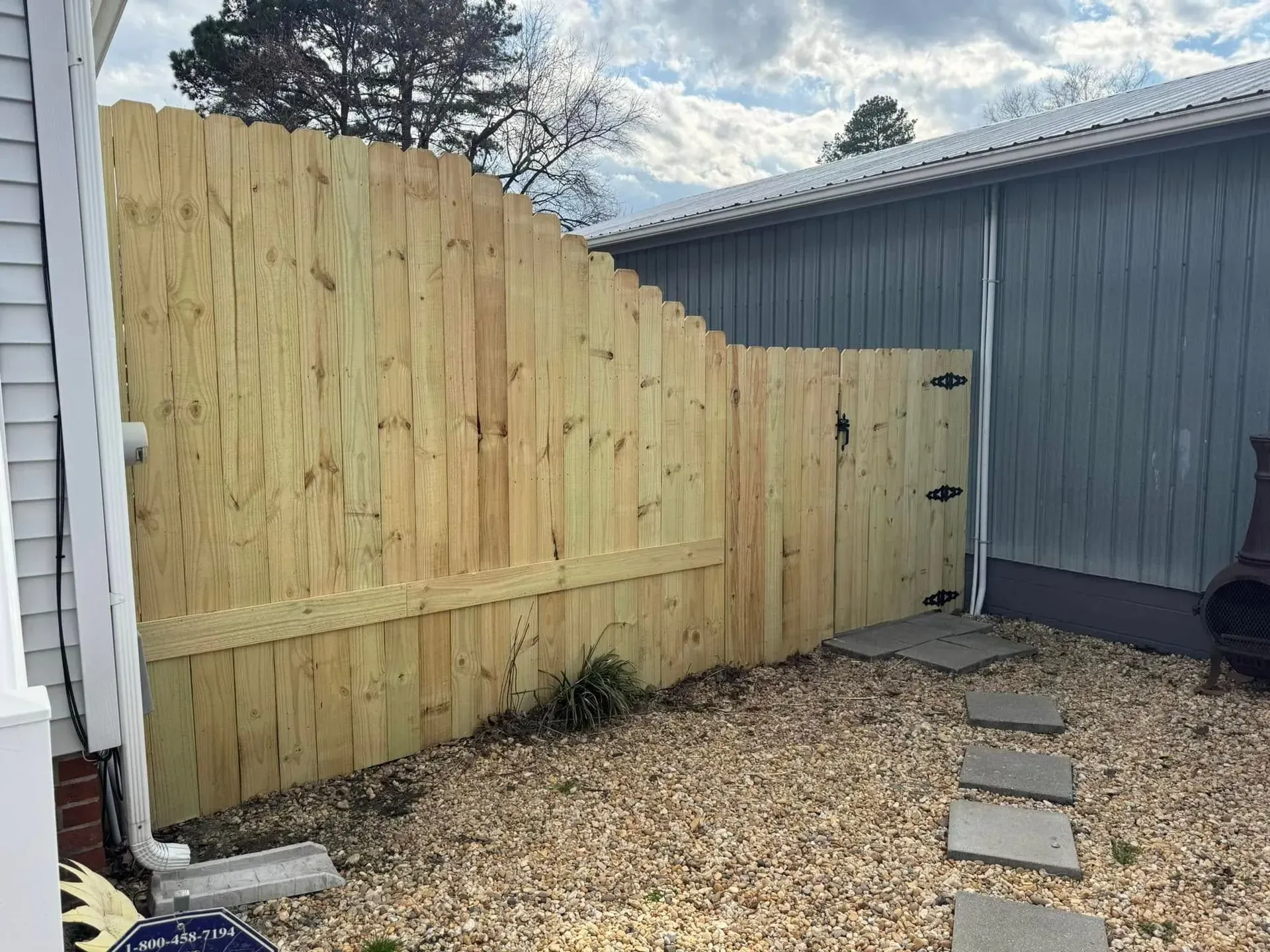 Brown wooden fence in a yard next to a building on a sunny day. Brown wooden fence in a yard next to a building on a sunny day.