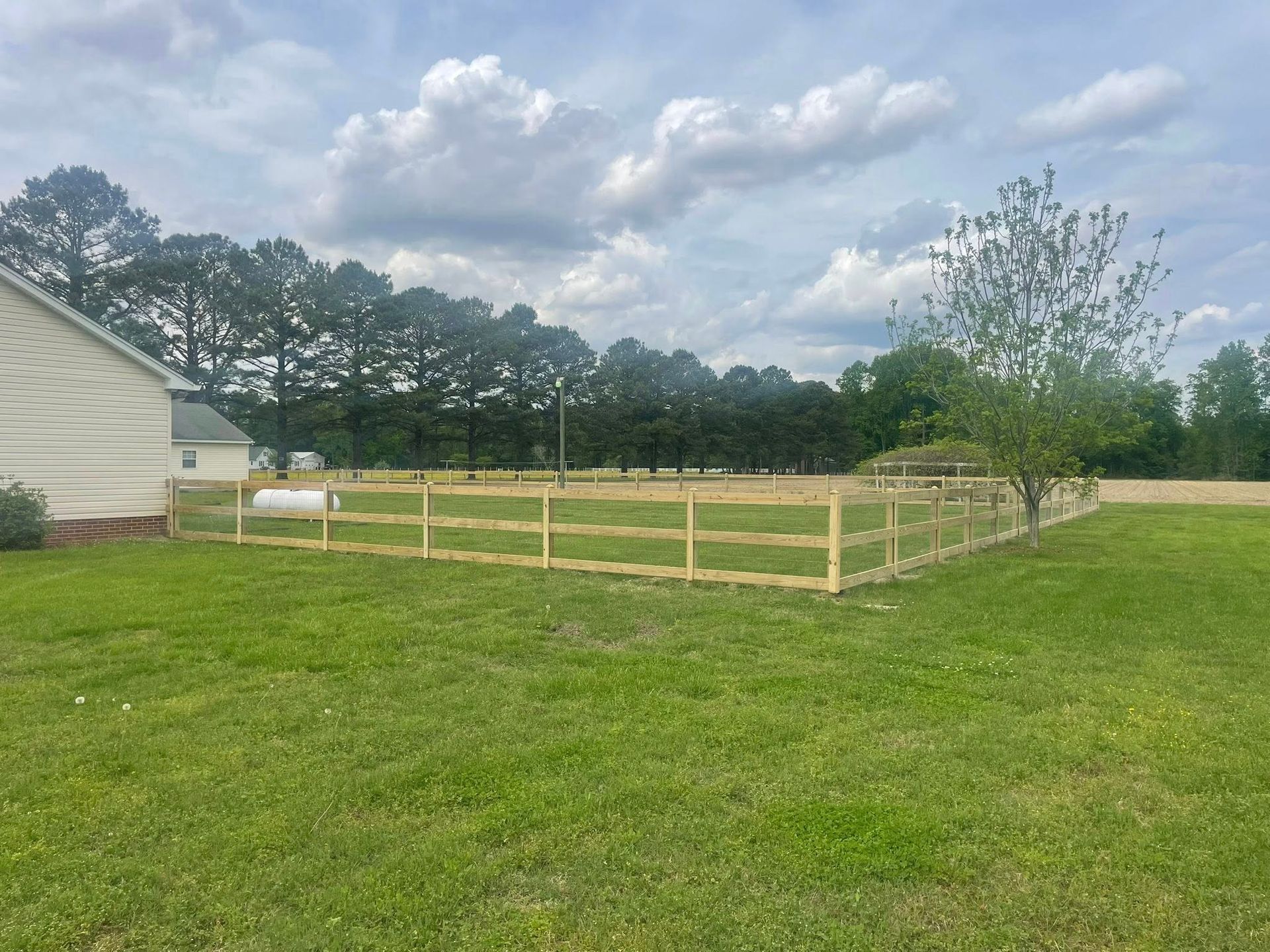 Wooden fence with two black metal gates and driveway. Wooden fence with two black metal gates and driveway.