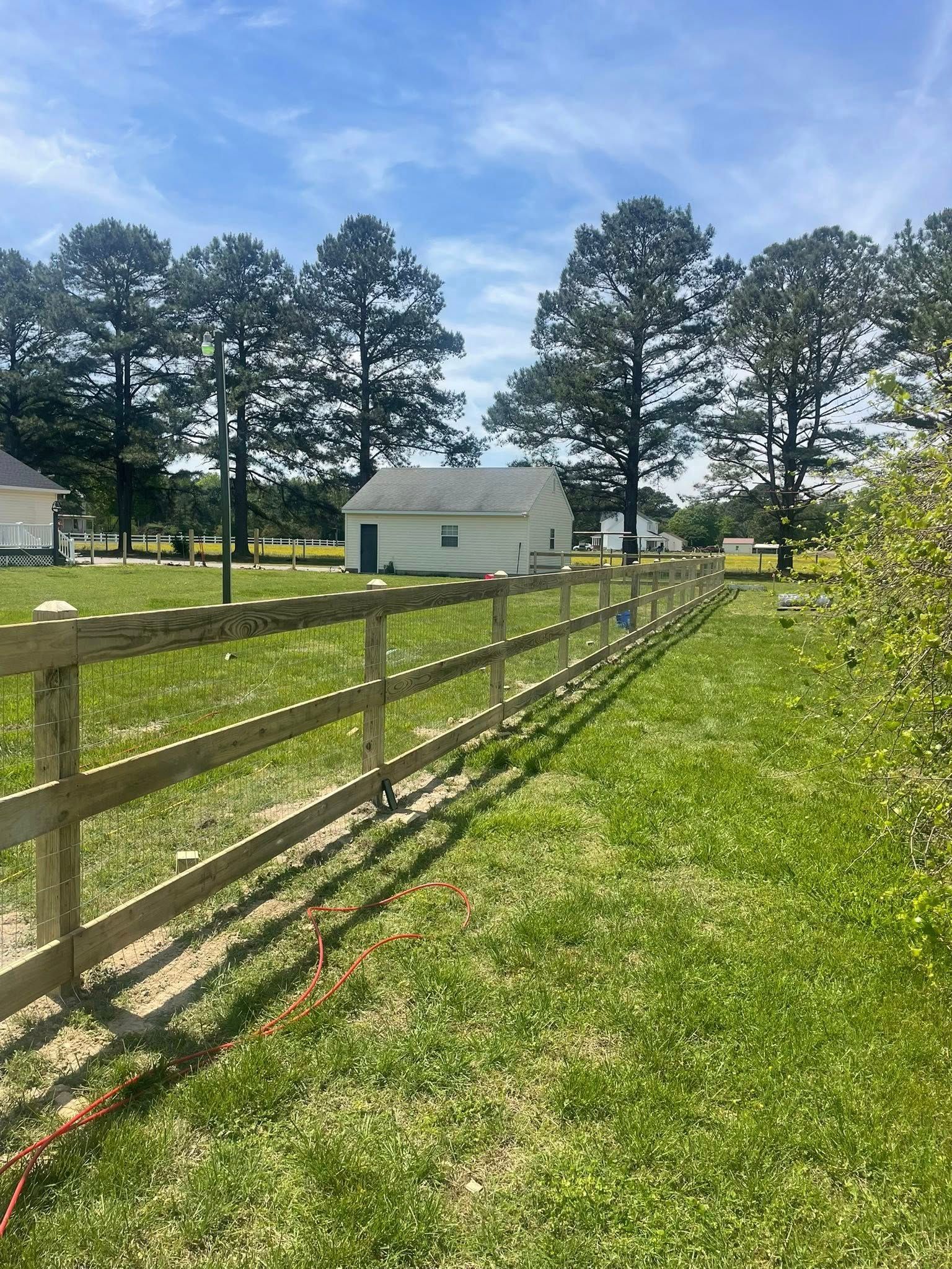 Wooden fence with three sections, stained light brown, next to a building. Wooden fence with three sections, stained light brown, next to a building.