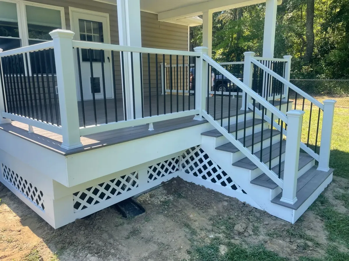 White porch with black railings and steps; lattice skirting. White porch with black railings and steps; lattice skirting.