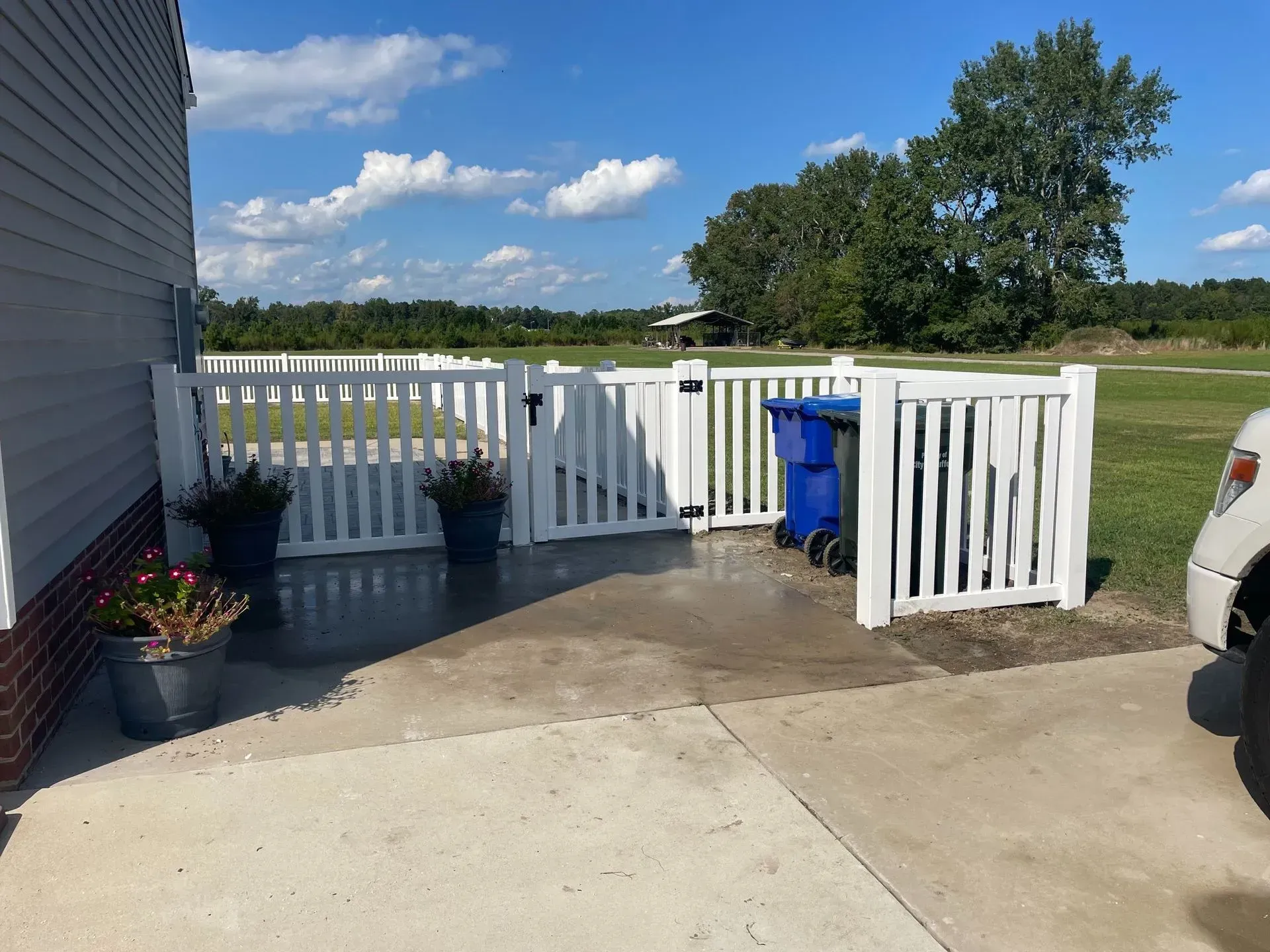 Wooden fence with two black metal gates and driveway. Wooden fence with two black metal gates and driveway.