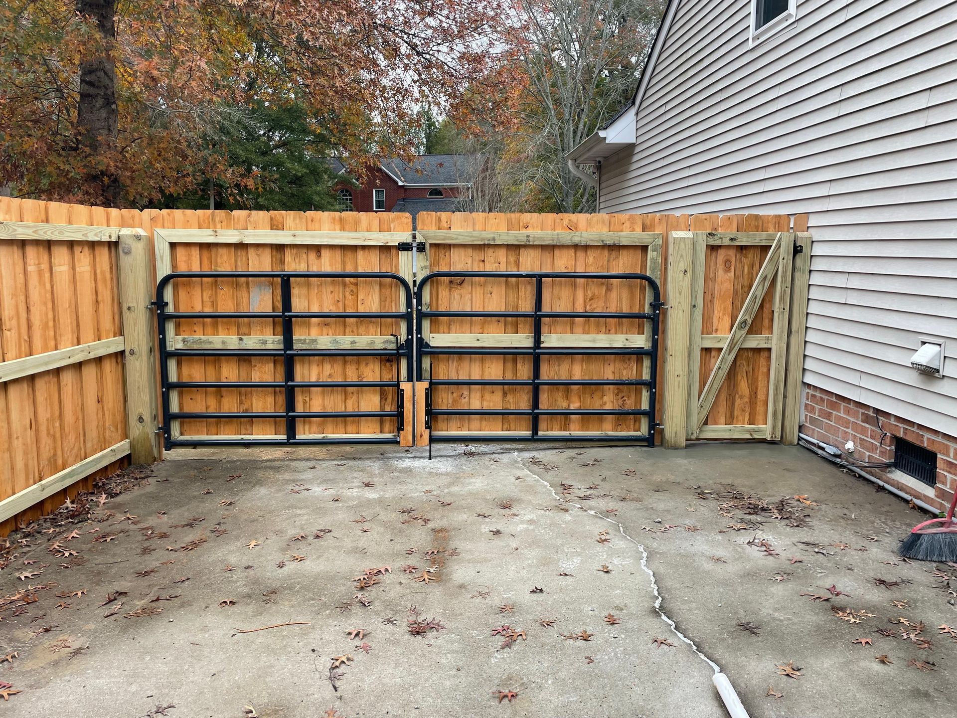 Wooden fence with black metal gates in a yard.