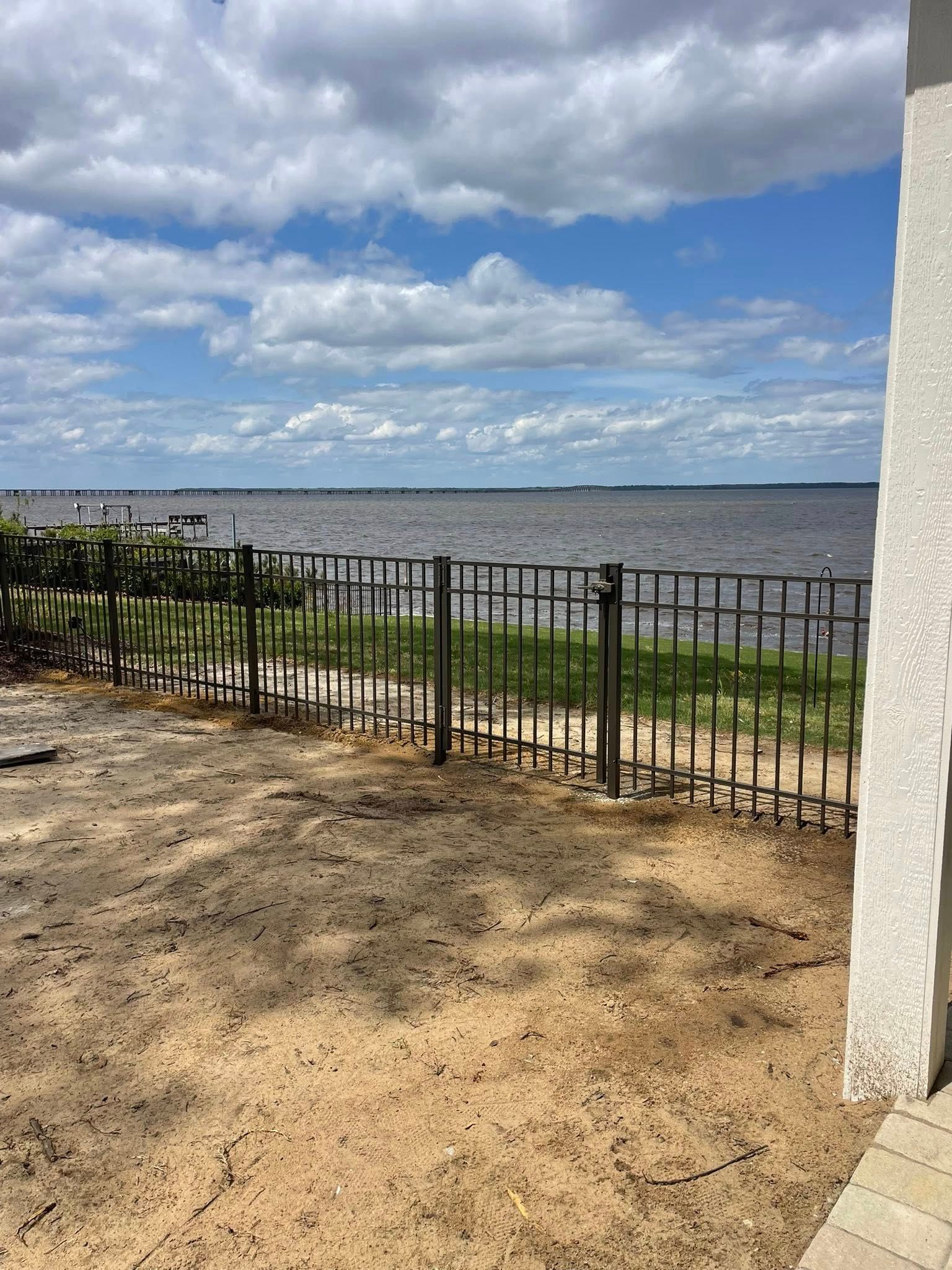 A gray and white deck with black railing and steps attached to a house with a covered porch.