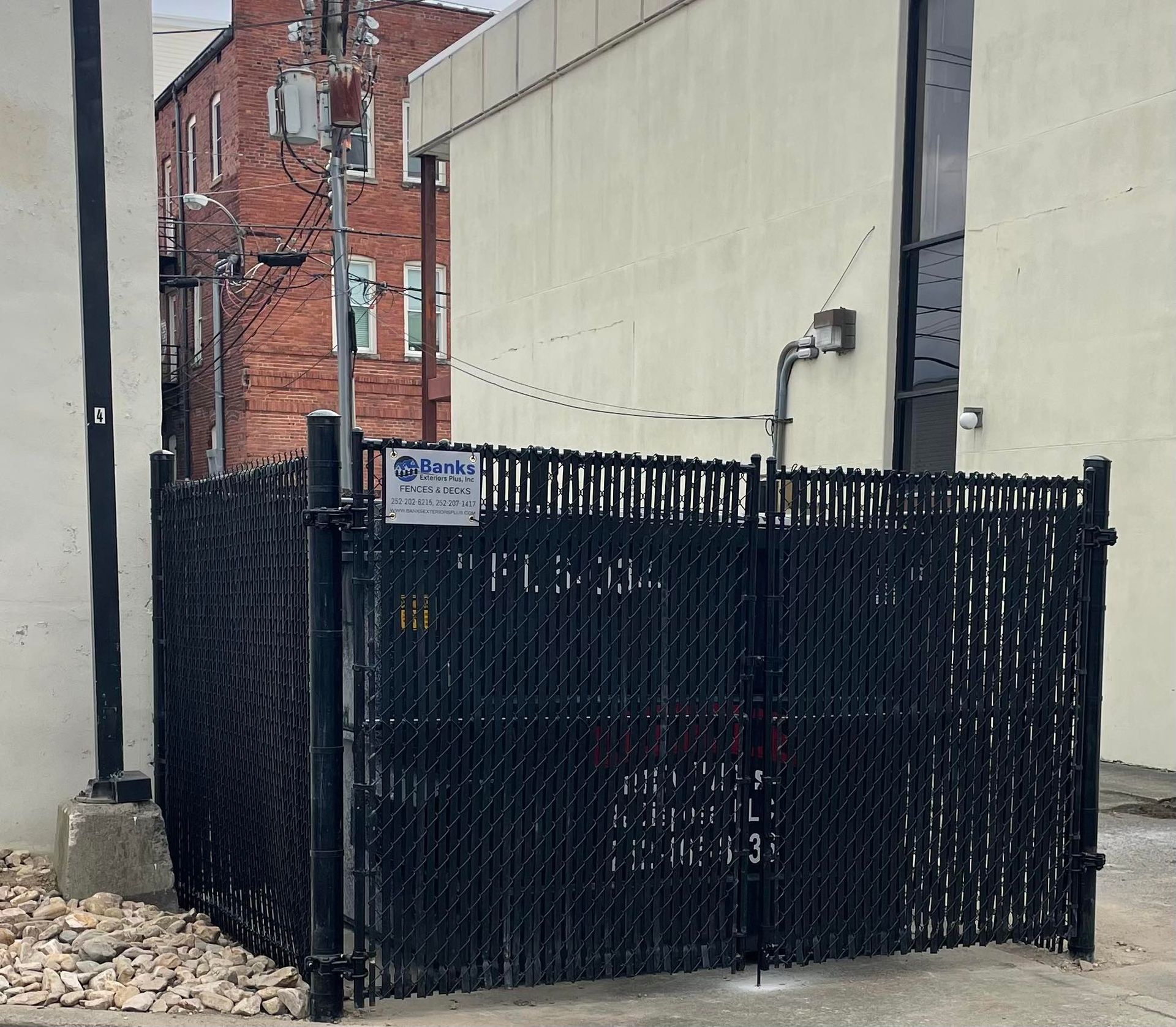 Wooden fence with two black metal gates and driveway. Wooden fence with two black metal gates and driveway.