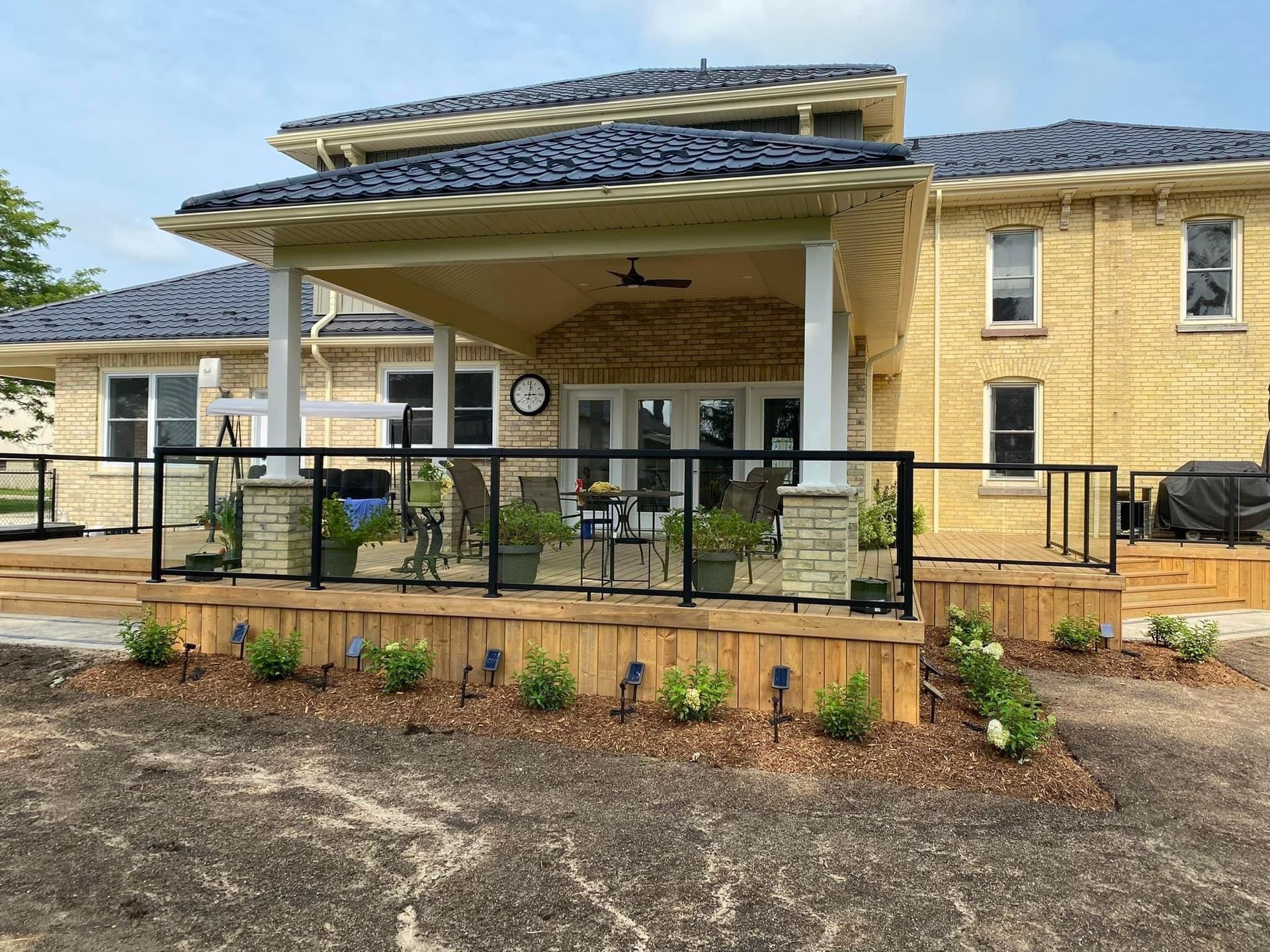 A large yellow house with a large deck and a covered porch built by Ironside Construction