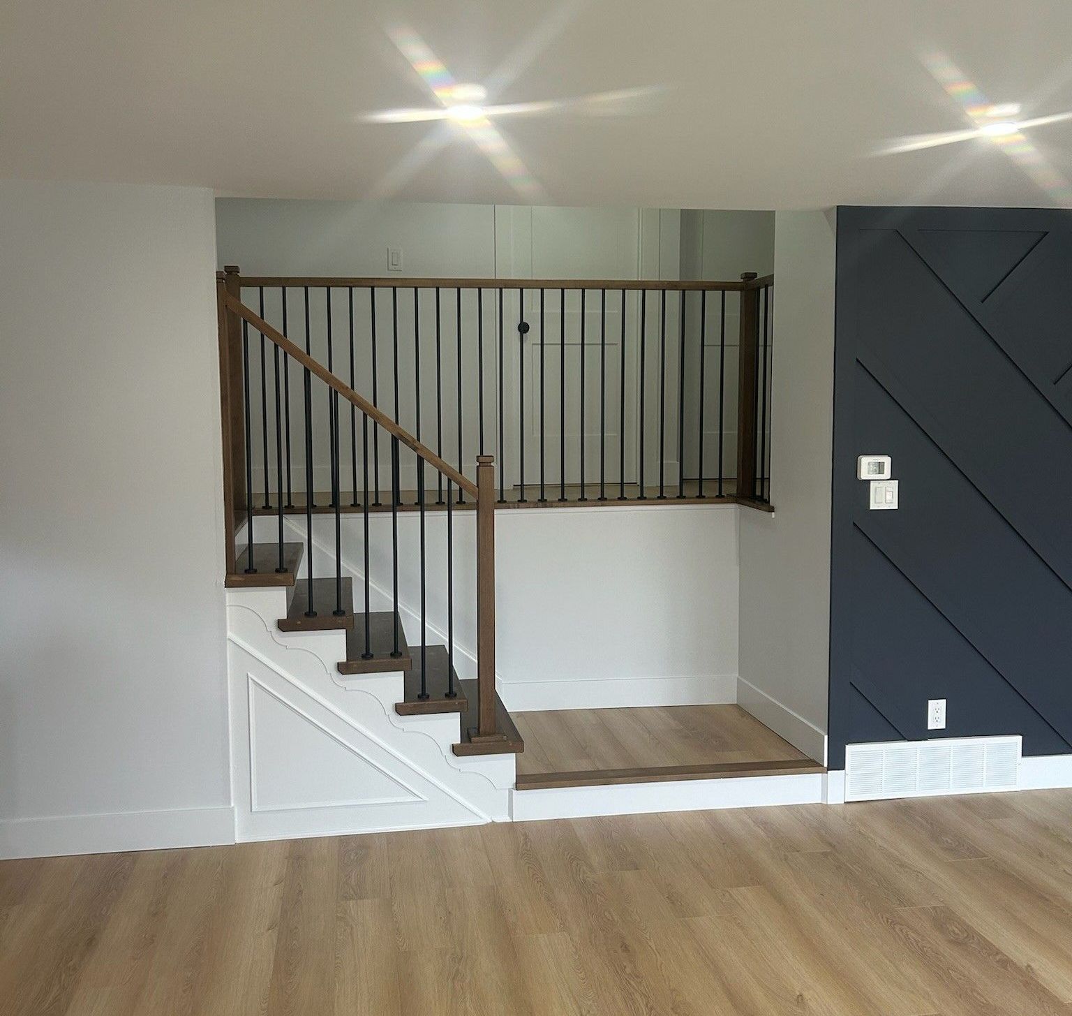 There is a staircase in the middle of the room with a railing built by Ironside Construction
